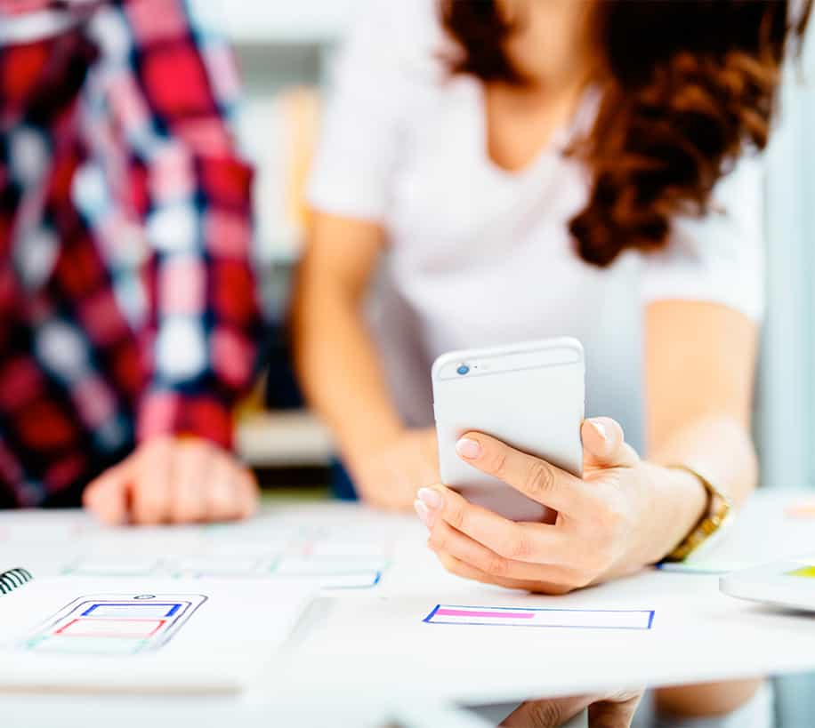 Blured picture of a woman checking her mobile phone while looking over building plans