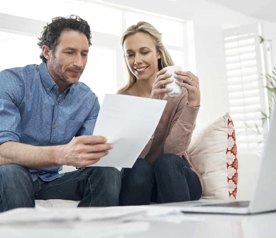 Couple sitting on a lounge looking over a deprecation quote while drinking a coffee